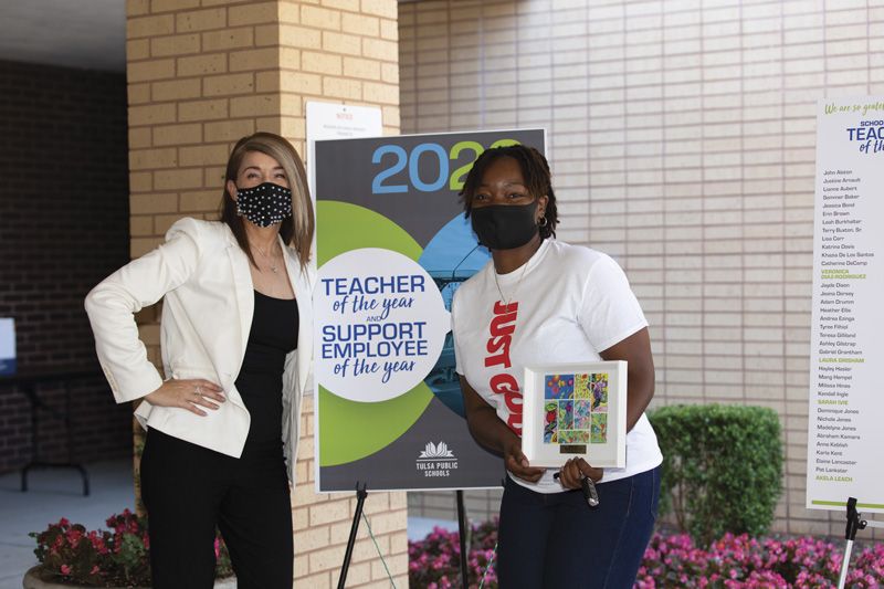 Dr. Gist with a school staff member in front of a Teacher of the Year and Support Employee of the Year poster.