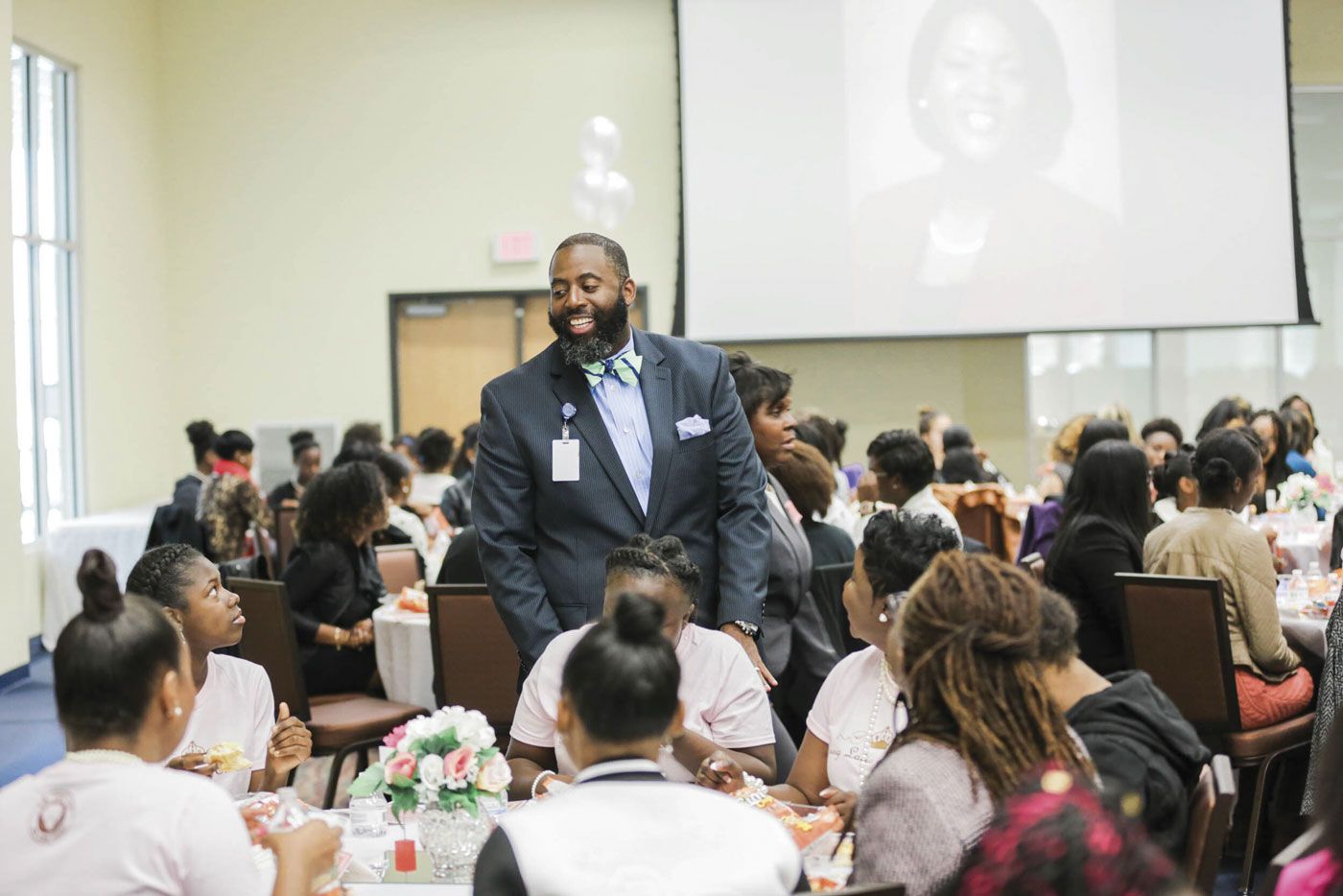 Dr. Barron Davis greets a table of young people during a luncheon.