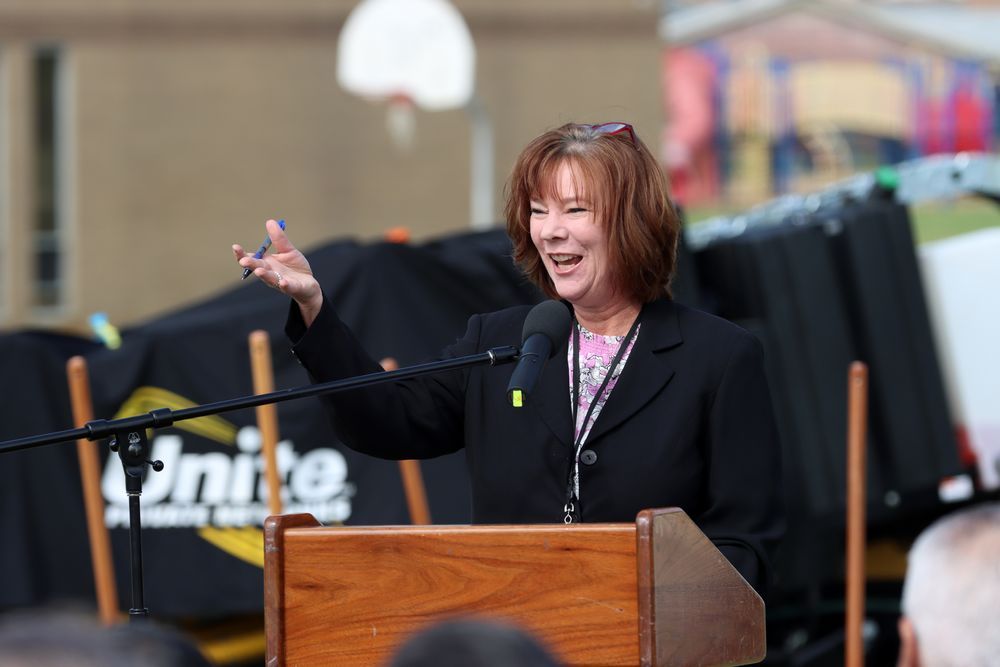 Anita Foster speaks at a podium before an unpictured crowd