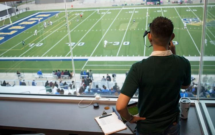 Rojas looks out at a soccer game with his commentator headset on.