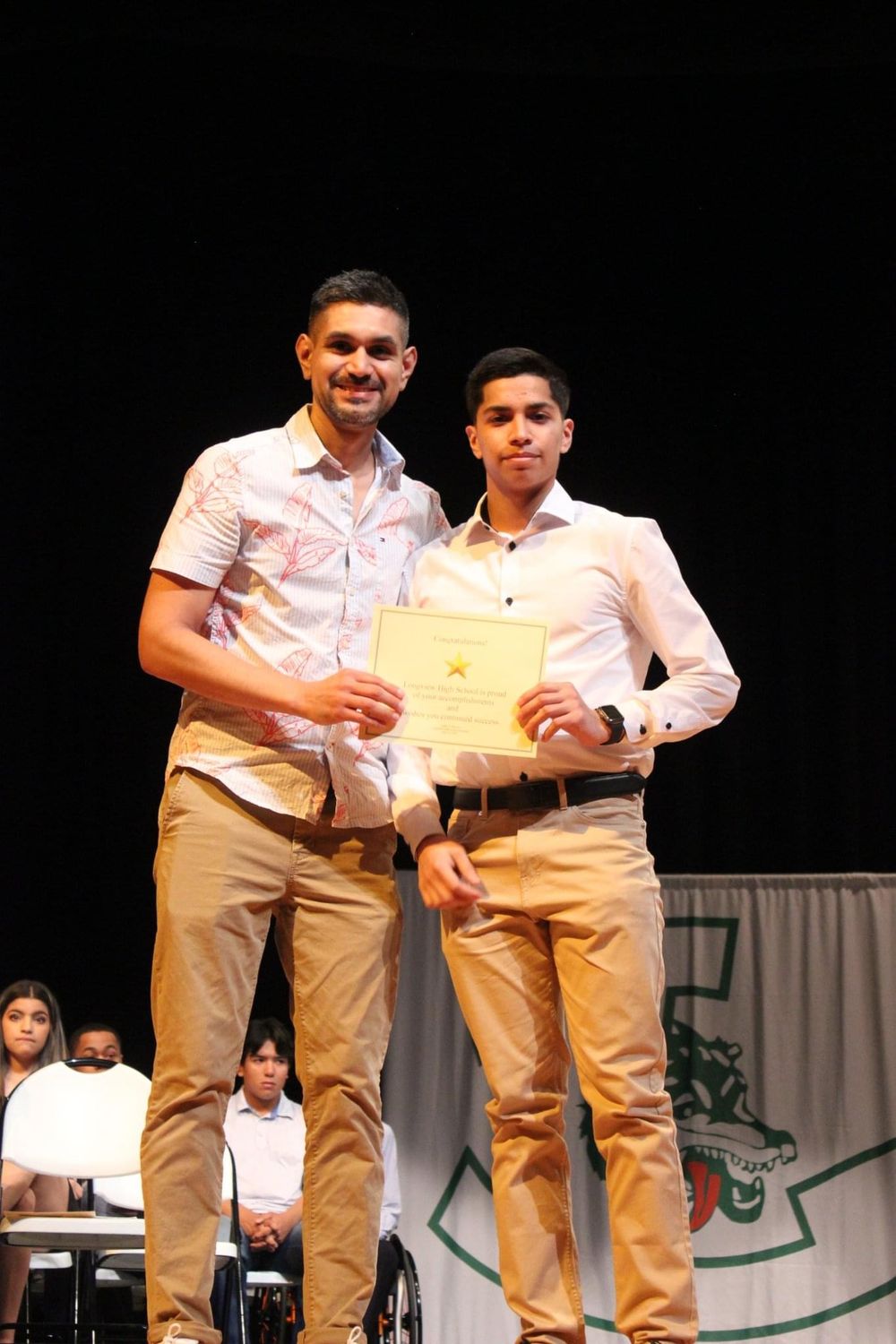 Rojas stands with student holding a scholarship certificate.