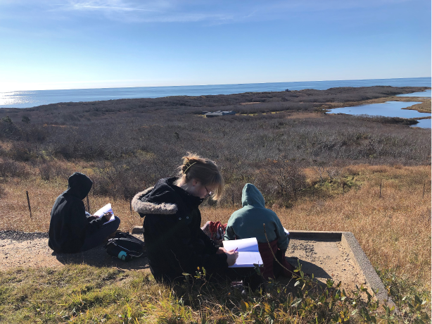 Photograph of three students from Falmouth School District journaling at the Outer Cape