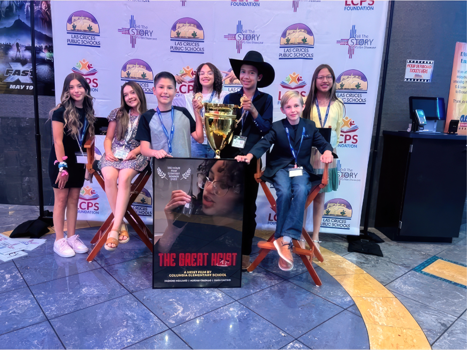 Photograph of seven student filmmakers with a trophy and poster of their film, The Great Heist