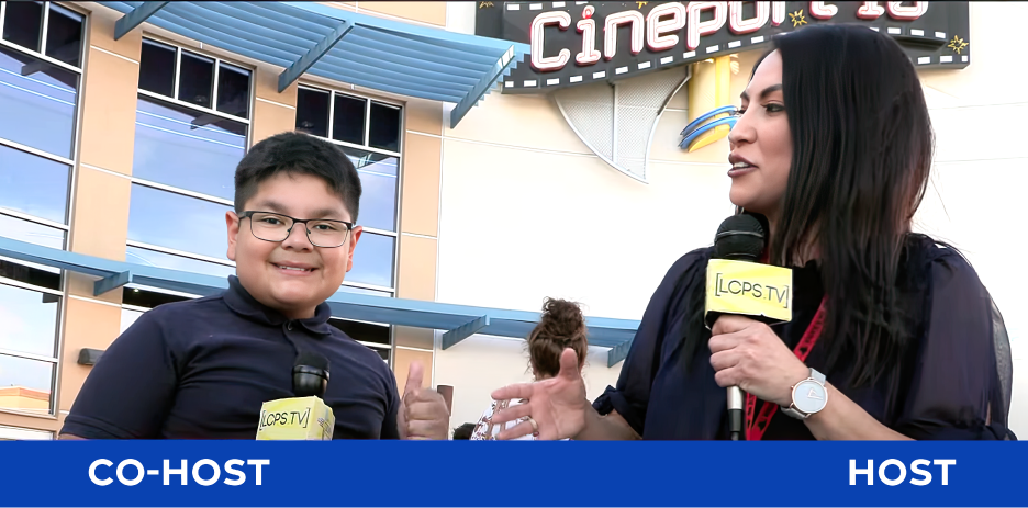 Screen capture of two hosts in front of movie theater for red carpet premiere