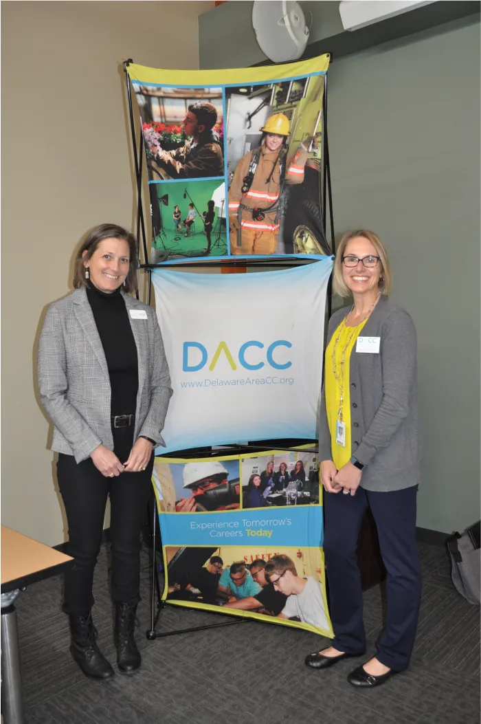Photograph of Alicia Mowry and DACC staff member next to school banner